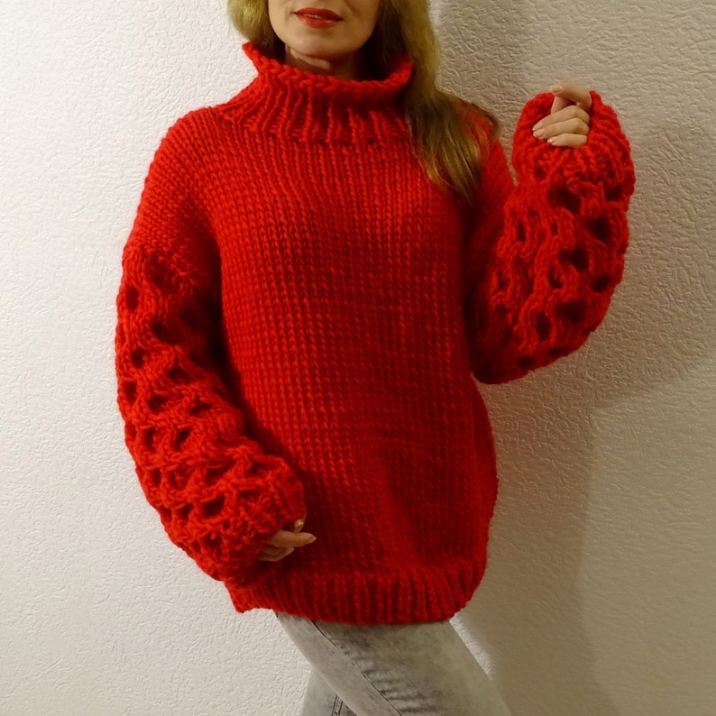 May include: A red knitted sweater with a turtleneck and large, open-weave sleeves.