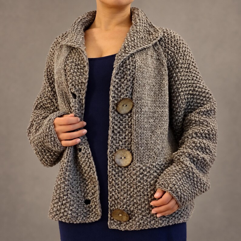 Open front view of a hand knit wool cardigan showing the collar, textured panels, coconut buttons and buttonholes.