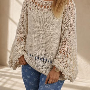 Hand knit off white cotton boho sweater with oversized fit, open knit texture and wide bell sleeves, photographed in soft natural window light.
