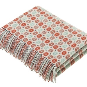 May include: A soft, woven throw blanket with a geometric pattern in shades of red, green, and white. The blanket has a fringed edge.