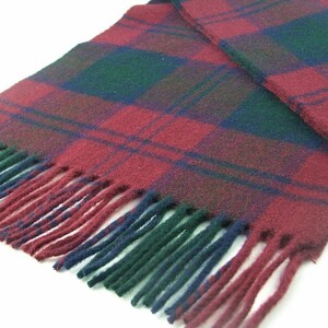 May include: A red, green and blue plaid scarf with fringe on the ends.
