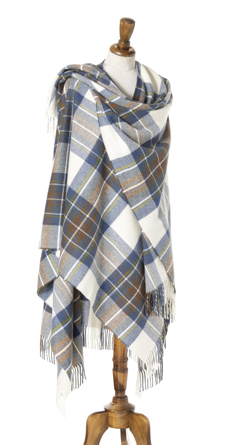 May include: A white, blue, and brown plaid shawl with fringe on a wooden mannequin.