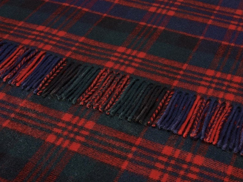 May include: A red, black, and blue plaid throw blanket with fringe. The blanket is made of soft, warm wool and is perfect for snuggling up on the couch.