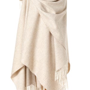 May include: A beige herringbone patterned wool shawl with fringe on a wooden mannequin.