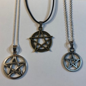 May include: Three silver necklaces with pentagram pendants. The pendants are different sizes and styles. The necklaces are on a white background.