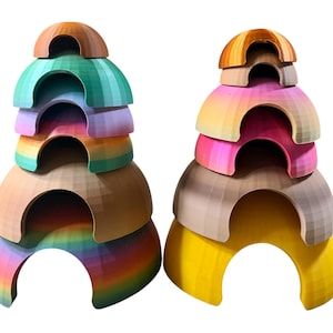 May include: Two colorful, stacked, semi-circular structures. One features a rainbow of colors, while the other has a gradient of pinks, yellows, and browns. Each structure has a rounded top and open arches.