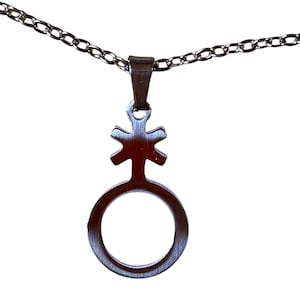 May include: A silver-colored pendant necklace featuring a stylized symbol. The pendant has a circular base with a vertical line extending upwards, topped with a cross-like design. The chain is made of small, interconnected links.