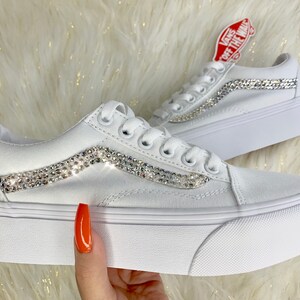 Könnte beinhalten: Weiße Vans-Sneaker mit Plateau und einem glitzernden Strass-Streifen an der Seite. "Vans Off The Wall" ist an der Seite des Schuhs aufgedruckt.