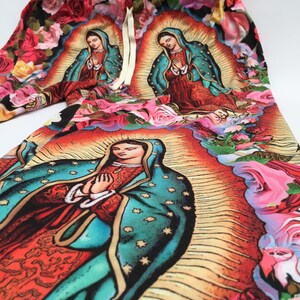 May include: A pair of colorful pants with a floral print featuring an image of the Virgin Mary. The pants have a drawstring waist and are made of a soft, comfortable fabric.