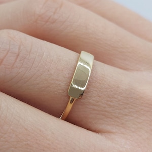 Peut inclure: Une bague simple en or avec un dessus plat et rectangulaire.