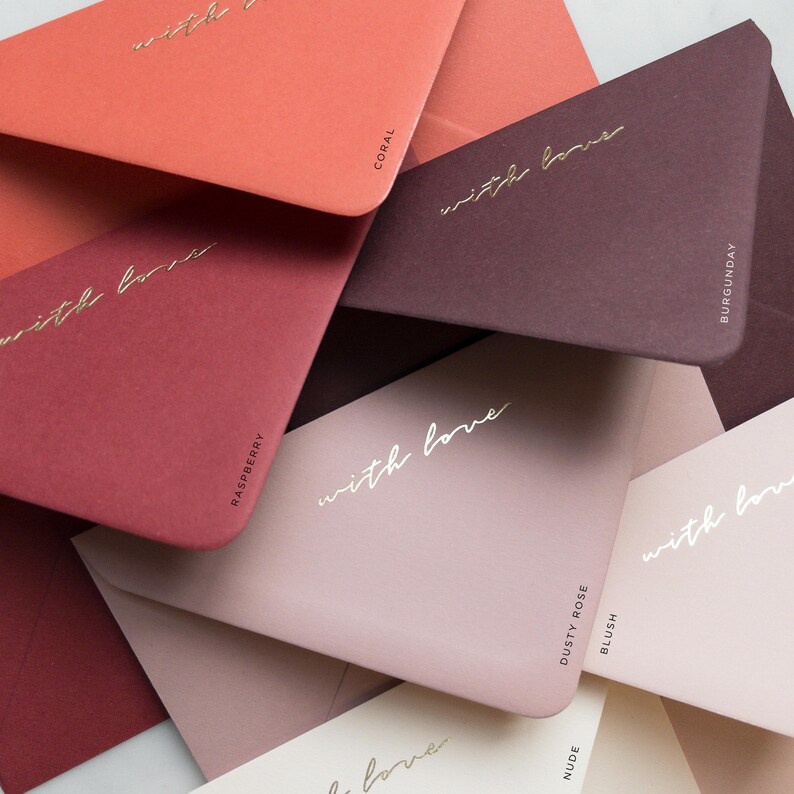 Pode incluir: Uma cole&ccedil;&atilde;o de envelopes coloridos em tons de coral, framboesa, bord&ocirc;, rosa empoeirado e nude. Cada envelope tem as palavras "with love" em escrita dourada. Os envelopes s&atilde;o rotulados com seus nomes de cores.