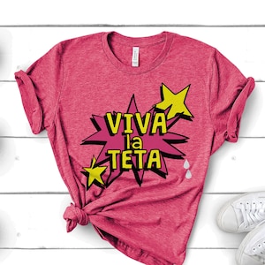May include: A pink t-shirt with a graphic print of a yellow star and the text "VIVA la TETA" in a comic book style.