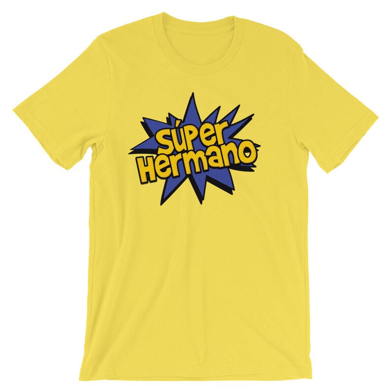 May include: A yellow t-shirt with the words "Super Hermano" in a blue and yellow comic book style design. The text is inside a blue starburst shape. The shirt is made of a soft material.