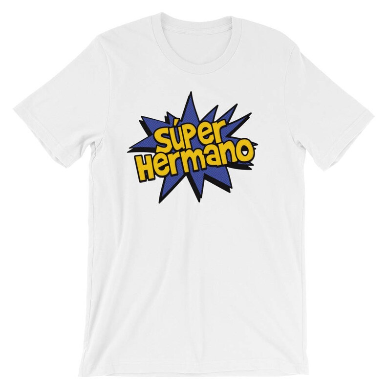 May include: White t-shirt featuring the text "Super Hermano" in yellow and black, set against a blue starburst design. The shirt is made of a soft material and has a crew neck.
