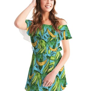 May include: A light blue off-the-shoulder dress with a tropical print featuring green leaves and yellow bananas. The dress has a ruffled neckline and a tie belt.
