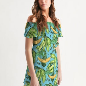 May include: A light blue off-the-shoulder dress with a tropical print of green banana leaves and yellow bananas.