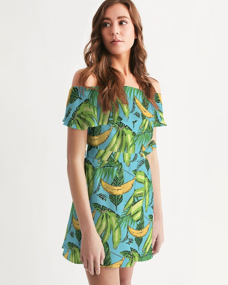 May include: A light blue off-the-shoulder dress with a tropical print of green banana leaves and yellow bananas.