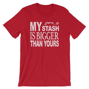 May include: Red short-sleeved t-shirt with white text that reads "My yarn stash is bigger than yours".