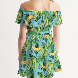 May include: A light blue off-the-shoulder dress with a tropical print featuring green leaves and yellow bananas.