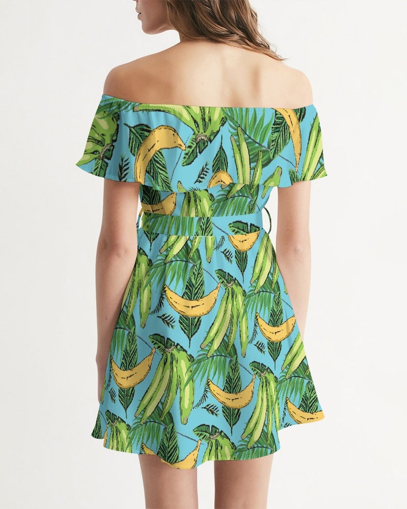 May include: A light blue off-the-shoulder dress with a tropical print featuring green leaves and yellow bananas.