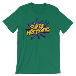May include: Green t-shirt with the text "S&uacute;per Hermano" in yellow and blue, a comic book style design. The text is centered on the chest of the shirt. The shirt is made of a soft material.
