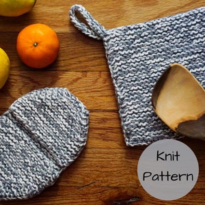 Op de afbeelding: Een gebreide grijze en witte pannenlap met een lus, een bijpassende ovenwant en een houten lepel rusten op een houten oppervlak. Een mandarijn en een citroen zijn ook aanwezig. De afbeelding bevat de tekst "Knit Pattern".