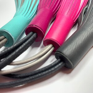 May include: Four leather tassels in turquoise, pink, gray, and silver. The tassels are attached to cords that are braided together.