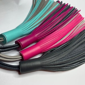 May include: Three leather tassels in turquoise, pink, and gray with black, gray, and white cords.
