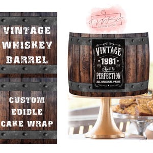 以下が含まれることがあります： ヴィンテージウイスキー樽のようにデザインされた、カスタムの食用ケーキラップ。デザインには「VINTAGE 1981 Aged to Perfection All Original Parts」の文字が含まれています。ケーキラップは、金のケーキスタンドに表示されています。