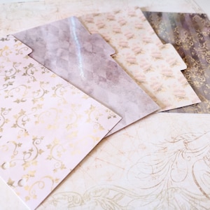 Puede incluir: Cuatro separadores de papel decorativos con diferentes patrones. Los separadores son rosas, marrones y dorados con diseños florales y geométricos.