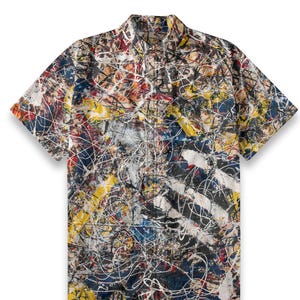 Op de afbeelding: Een overhemd met korte mouwen en knopen met een abstracte print in tinten blauw, geel, rood, wit en zwart.