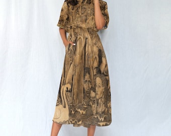 May include: A brown midi dress with a black and white print of faces and a swan. The dress has a short sleeve and a cinched waist.