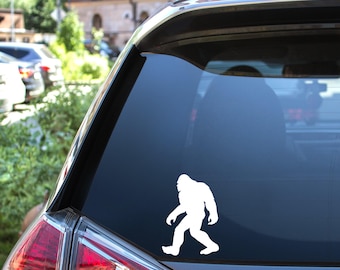 May include: White vinyl sticker of a Bigfoot silhouette walking on a car window.