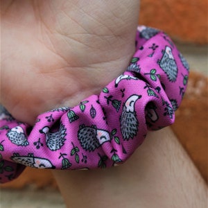 Puede incluir: Un coletero rosa con un patrón repetido de erizos grises y hojas verdes.