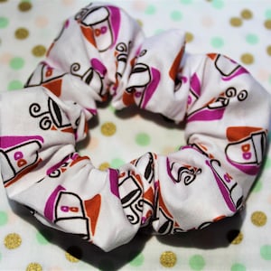 May include: White scrunchie with a pink and orange print of coffee cups with the text "DD" on them.