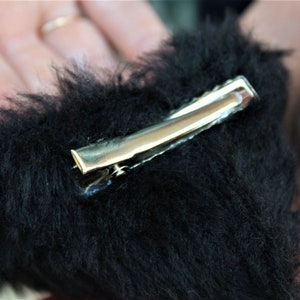 Pu&ograve; includere: Un fermaglio per capelli a forma di cuore nero e soffice con una chiusura in metallo argentato.