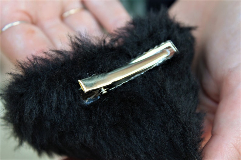 Pu&ograve; includere: Un fermaglio per capelli a forma di cuore nero e soffice con una chiusura in metallo argentato.