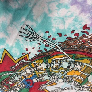 Puede incluir: Una tela te&ntilde;ida con un dise&ntilde;o gr&aacute;fico colorido que presenta esqueletos, rosas y una estructura de madera. El dise&ntilde;o incluye elementos rojos, amarillos, azules y verdes, con el texto "&copy;1993 GDM INC."