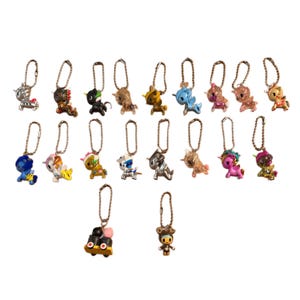 May include: A selection of miniature unicorn keyrings in a variety of colours and designs. The keyrings feature metallic finishes and are attached to metal chains. Colours include silver, gold, blue, pink, and black. Each keyring has a unique design.