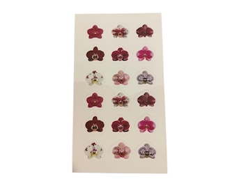 Könnte beinhalten: Ein Bogen mit Aufklebern mit verschiedenen Orchideenblüten-Designs. Die Aufkleber zeigen eine Reihe von Farben, darunter tiefe Rottöne, Rosa- und Lilatöne, mit komplizierten Details. Die Aufkleber sind auf einem weißen Hintergrund angeordnet.