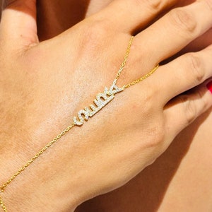 May include: A gold chain bracelet with a diamond-encrusted nameplate that reads "unique". The bracelet is worn on a person's wrist and hand.
