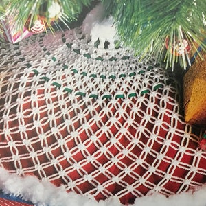 May include: White crocheted Christmas tree skirt with a red and green border. The skirt is decorated with white and green yarn.