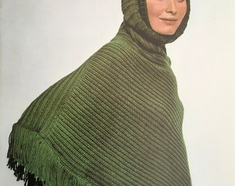 May include: A green knitted poncho with a matching hood and fringe trim. The poncho is made of a soft, warm yarn and is perfect for cold weather.