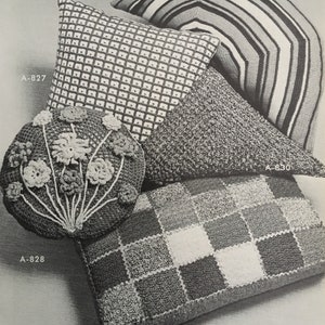 May include: Five crocheted cushions in various shapes and patterns. A square cushion with a checkered pattern, a round cushion with a floral design, a triangular cushion with a textured surface, and two rectangular cushions with striped and checkered patterns.