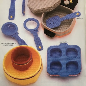 May include: A set of 10 plastic canvas kitchen tools, including a potato masher, meat fork, skillet with lid, spatula, muffin pan, ice cream scoop and tea strainer, mixing bowls, and a rolling pin. The tools are all in various colors, including blue, yellow, red, and brown.