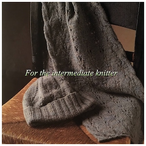 May include: A grey knitted scarf with a cable knit pattern and a crocheted hat. The text "For the intermediate knitter" is visible on the scarf.