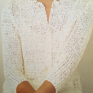 May include: A white crocheted cardigan with a button closure. The cardigan has a delicate openwork pattern.