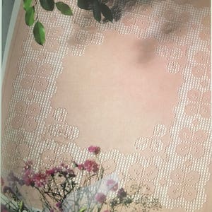 Op de afbeelding: Een roze stoffen tafelkleed met een wit geborduurd bloemenpatroon rond de rand.