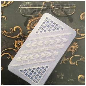 Peut inclure: Un rectangle de tissu blanc avec un motif brodé bleu et blanc. Le tissu présente un motif géométrique avec un motif répétitif de triangles et de carrés.