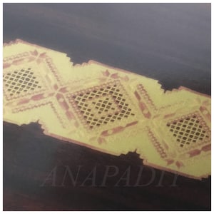 May include: A yellow lace trim with a geometric pattern. The lace is on a dark brown surface with the word "ANAPADI" printed in white.